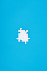top view of assembled white puzzles isolated on blue, business concept