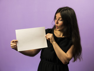 Surprised Young Brunette Girl holding empty blank white board. Leaflet presentation. Pamphlet hold...