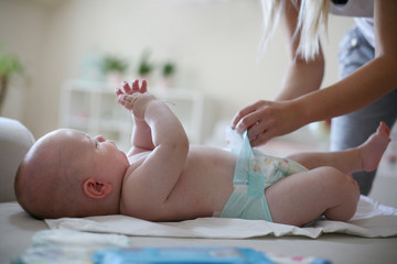 Young mother changing diaper baby boy. Close up