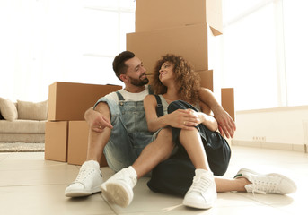 Fototapeta na wymiar married couple sitting near cardboard boxes in a new apartment