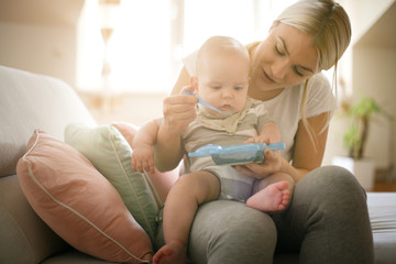 Mother feeding her little baby boy at home. Close up.