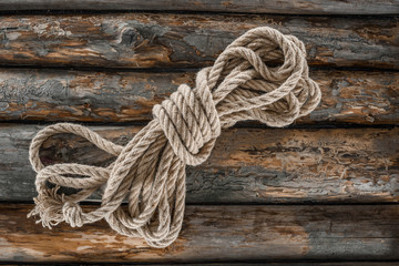 Fototapeta premium top view of tied nautical rope on grunge wooden surface