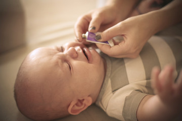 Mother with her baby boy using cream for teeth. Close up.