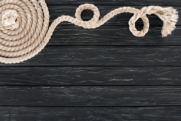 top view of white marine rope arranged in circle on dark wooden tabletop