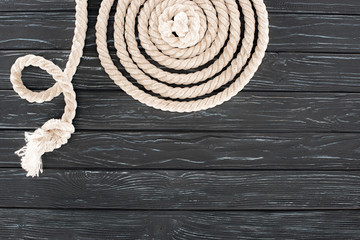 top view of white marine rope arranged in circle on dark wooden tabletop