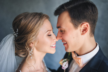 Beautiful newlyweds gently embrace in the studio. Close-up portrait of a newly-married couple.