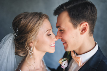 Naklejka premium Beautiful newlyweds gently embrace in the studio. Close-up portrait of a newly-married couple.
