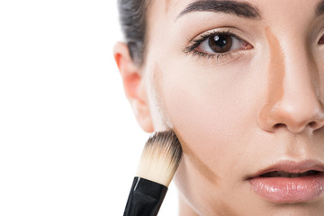 cropped image of beautiful girl applying foundation cream with brush isolated on white