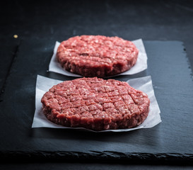 Raw ground beef meat burger cutlets on grey cooking background