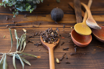 Spice cloves and a wooden spoon on a wooden table.