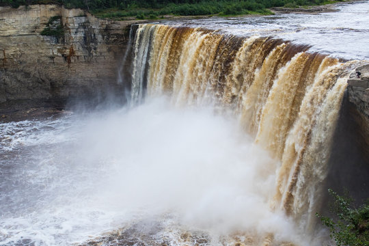 Unrecognizable people standing at the top of Alexandra Falls in the Northwest Territories, Canada, giving perspective as to the height of the falls