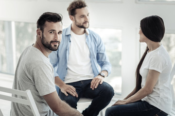 Fototapeta premium Positive mood. Nice positive cheerful man smiling and looking at you while visiting psychological session