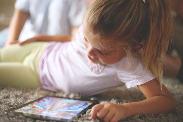 Little girl using digital tablet. Little girl playing game on tablet.