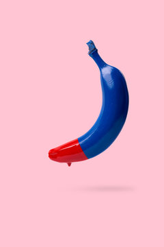 Blue banana with dripping red paint on pink background