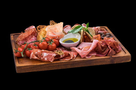 tasty plate of cheese, salami, prosciutto, cherry tomatoes over wooden board