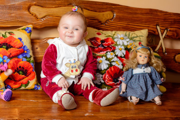 Little baby with a tail sits on a sofa with embroidered pillows and toys