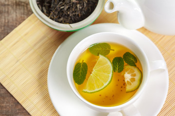 cup of black tea with mint leaves on a wooden table