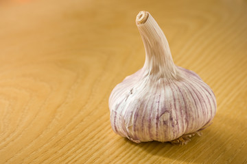 Head of garlic on a wooden table illuminated laterally.