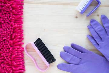 Cleaning Concept. Set of yellow, green, blue, red, white and pink cleaning tools: rags, sponges, brushes, dishwashing liquid, rubber gloves on the wooden background, top view, flat lay, close up