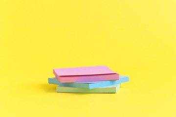 Pile of colorful sticky notes on pastel yellow background.