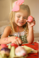 Toddler having fun painting Easter eggs.