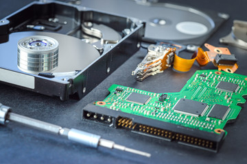 Obraz premium Disassembled hard disk drive inside close-up, spindle, actuator arm, read write head, platter, disassembly tools