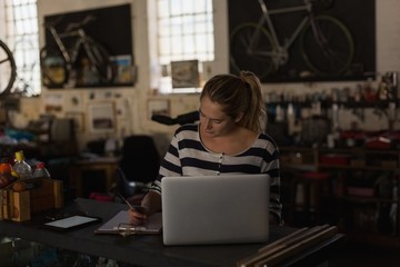 Female mechanic using laptop in workshop