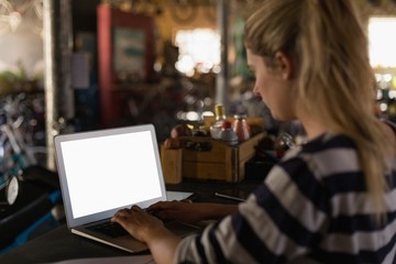 Female mechanic using laptop in workshop