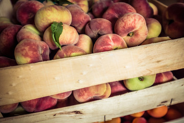 Close-up of saturn peaches in a wooden box. Peach harvest