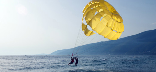 Parachute walk on the sea couple of loving people together on a yellow parachute over the water