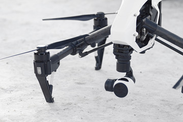 modern white quadcopter drone armed with camera landed on a snow