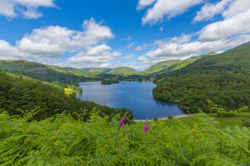 Beautiful landscape featuring Lake Grasmere and the surrounding mountains in the Lake District, UK. Wide angle lens gives the blue sky and puffy clouds a movement sensation.