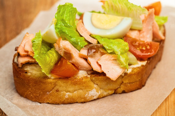 Salmon Sandwich Closeup. Salmon, eggs, lettuce and tomatoes on Bread