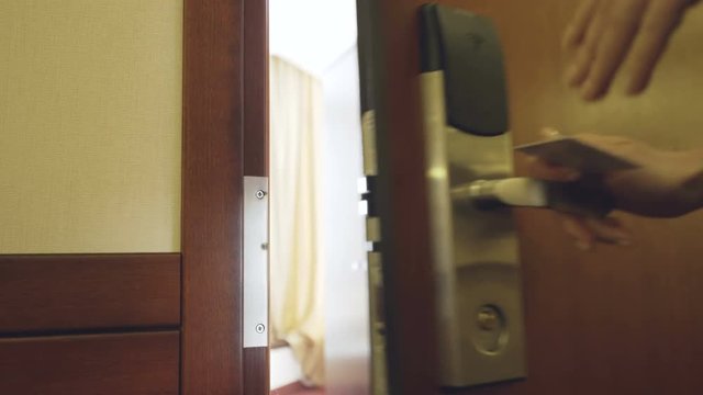 Closeup of businesswoman in suit open hotel room door using contactless key card and entering the room. Travel, business and people concept
