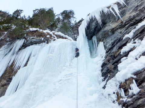 male ice climber high up on a steep ice fall in the Alps