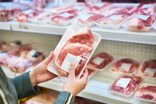 Buyer hands with pork meat at grocery
