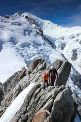 mountain guide and a male client on a rocky ridge heading towards a high summit in the French Alps near Chamonix