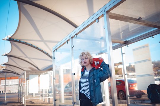 Woman holding skateboard at bus stop