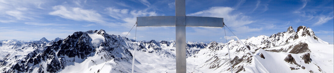 panorama view of winter mountain landscape in the Swiss Alps with a summit cross in the middle