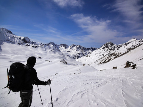 male backcountry skier looks at mountain landscape and his goal for the day's backcountry ski tour