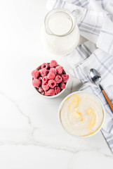 Healthy breakfast, semolina porridge with milk and raspberry, white marble table copy space top view