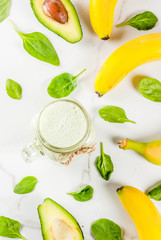 Healthy smoothie with banana and baby spinach, n white marble background copy space top view