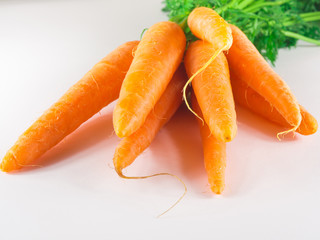 Pile of fresh orange carrots with green leaves over white background