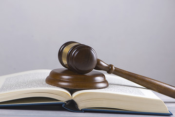 Wooden mallet used by a judge or at an auction next to a book. Concept
