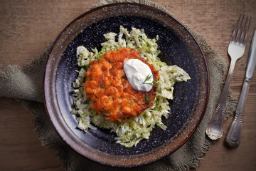 Salmon burger and cabbage salad in bowl on wooden table. Salmon fish cake and vegetables. overhead, horizontal