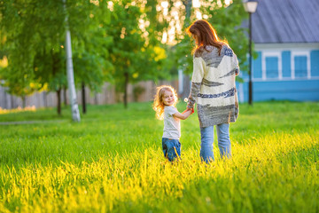 Fototapeta premium Mother and little daughter walking in spring sunny park