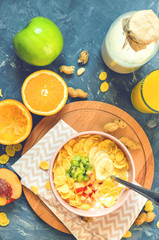 Delicious and healthy breakfast, top view. Milk, corn flakes, orange juice, orange, apple, nectarine, kiwi, banana, peanuts