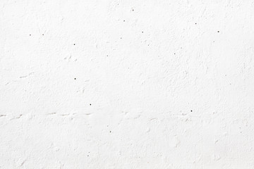 The texture of an old white wall painted with paint, on a bright spring sunny day