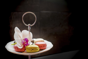 Tender pink and cream macarons and flower on black stone background. soft focus, Place for your text