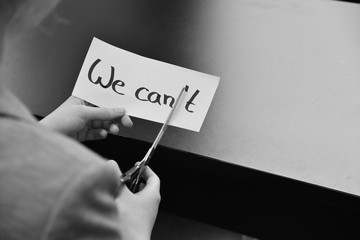 Business Frau schneidet Papier - "We can't" wird zu "We can"